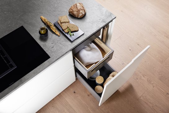 Kücheninsel in weiß von oben mit geöffneter Schublade , darin ein Brotsack