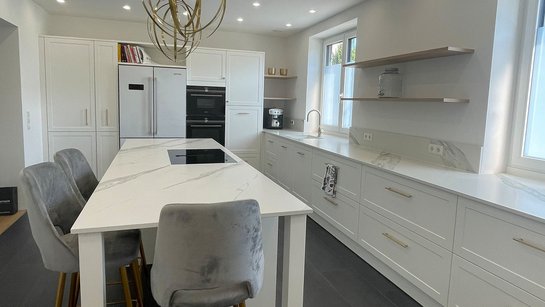 Große weiße Inselküche im Landhausstil mit an der Kücheninsel angebautem Esstisch