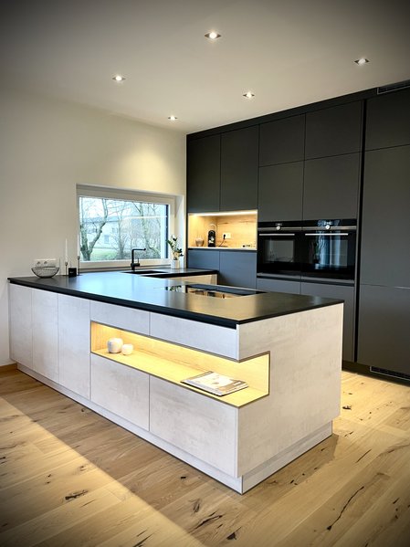 U-förmige Küche mit Kücheninsel in heller Betonoptik und deckenhohen Hochschränken in dunkelgrau