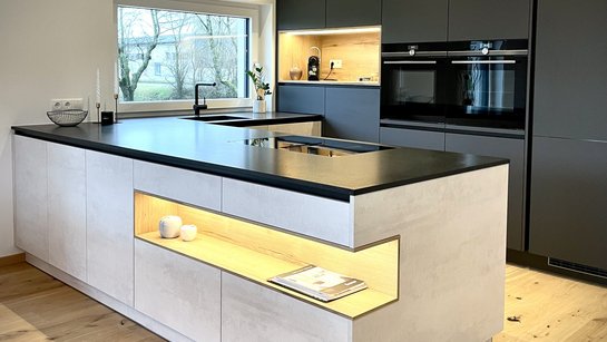 U-förmige Küche mit Kücheninsel in heller Betonoptik und deckenhohen Hochschränken in dunkelgrau