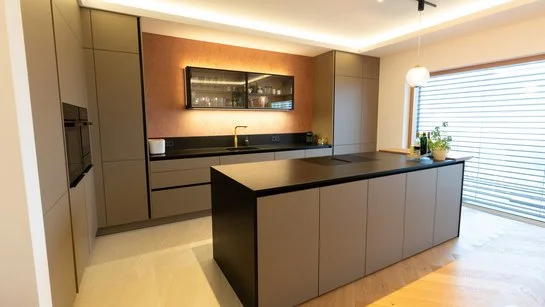 Blick auf die gesamte Küche mit klarer Linienführung, deckenhohen Hochschränken und der großzügigen Insel als zentrales Element.