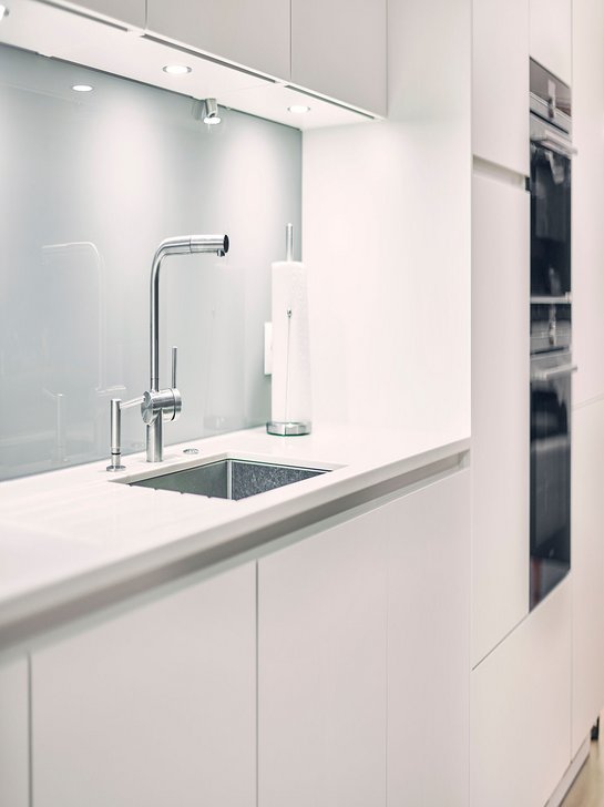 Weiße Küchenzeile mit Spülbereich mit einer Edelstahlarmatur und Edelstahlspüle