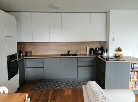 Kpompakte L-förmige Küche in weiß und grau mit Rückwand in Holzoptik