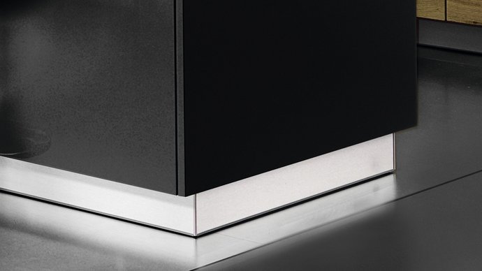 Ausschnitt einer dunklen Kücheninsel mit silbernem Sockel