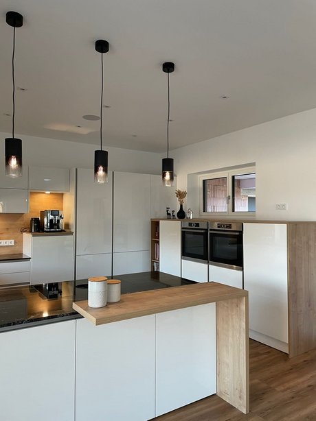 Ausschnitt einer weißen Hochglanzküche mit an der Kücheninsel angebauter Bar